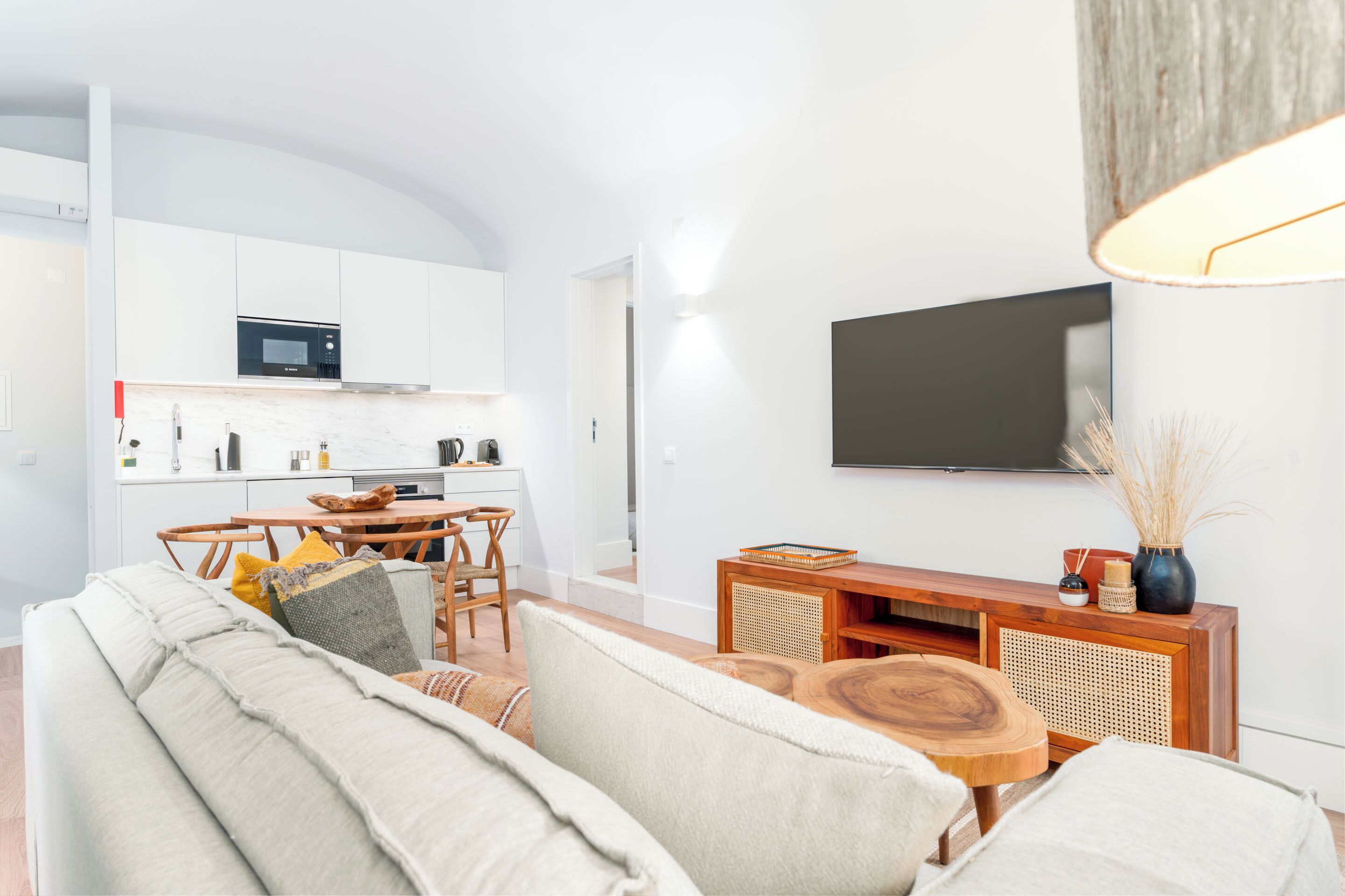 A modern living room with a sofa, coffee table, and a TV mounted on the wall.