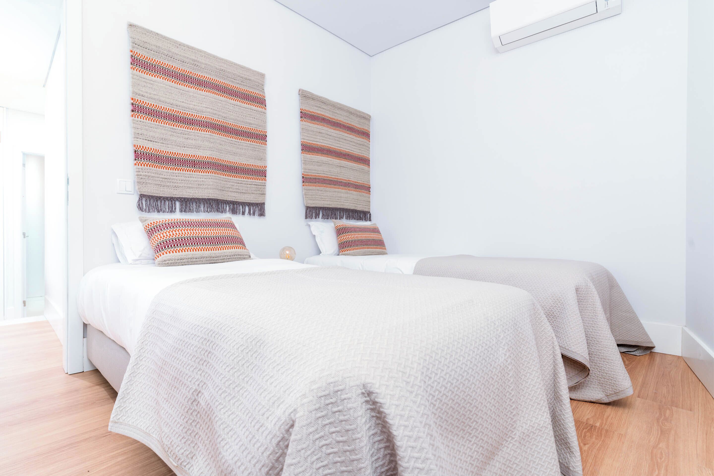 Un dormitorio moderno con dos camas, un ventanal grande y un ventilador de techo.