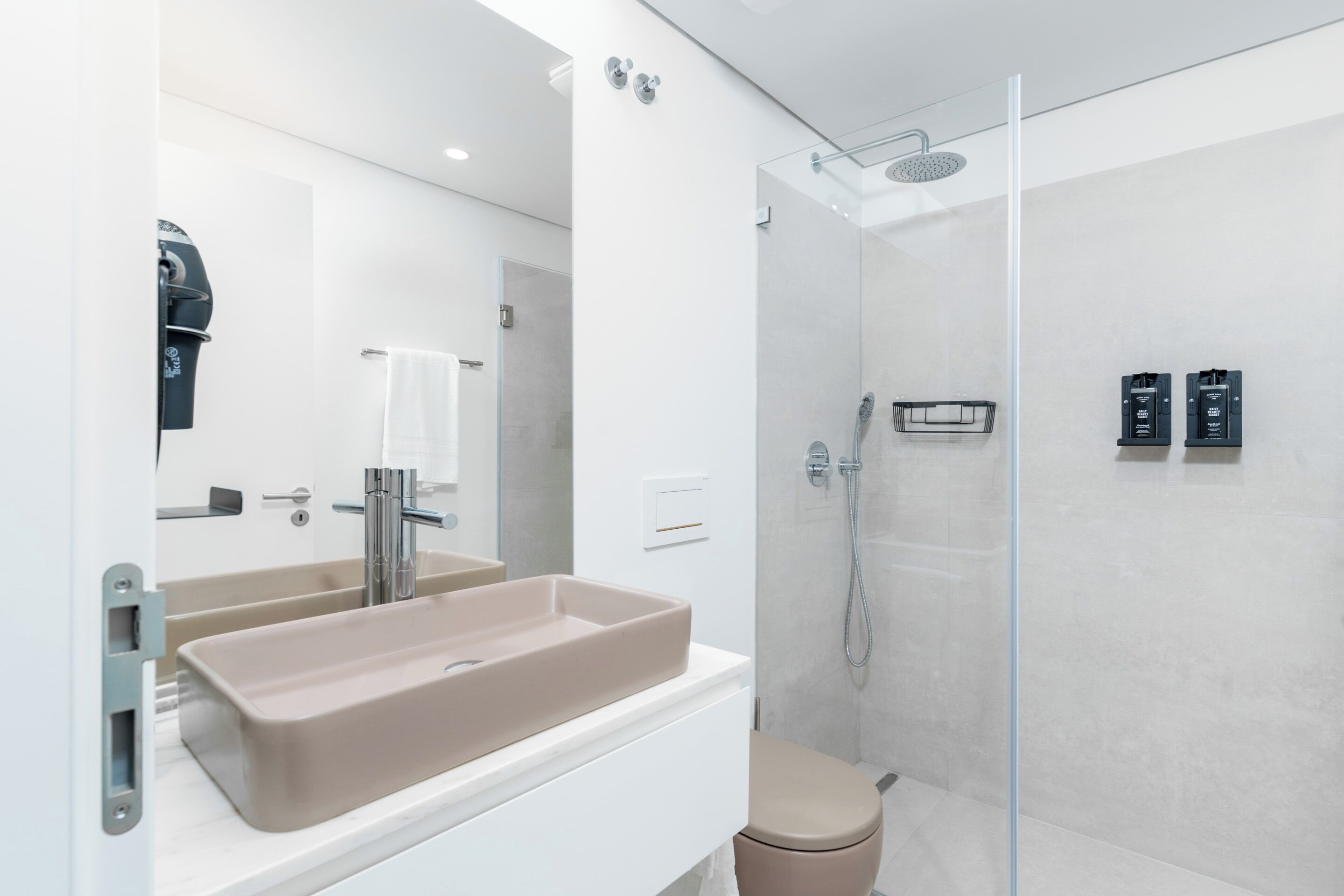 A modern bathroom with a beige sink, a glass shower enclosure, and a white toilet.