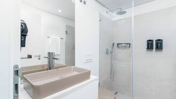 A modern bathroom with a beige sink, a glass shower enclosure, and a white toilet.