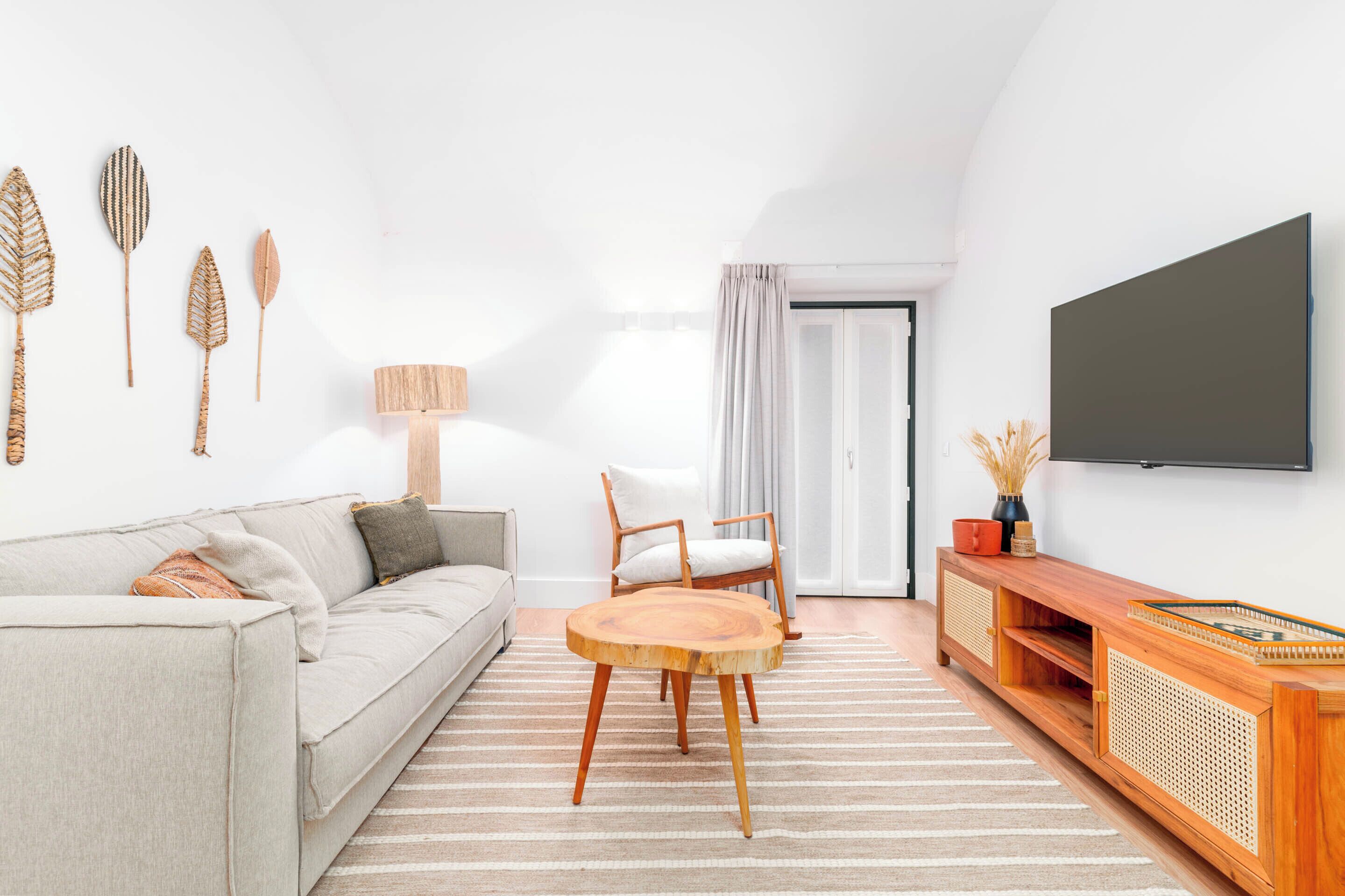 A modern living room with a sofa, chairs, a round wooden coffee table, a TV, and decorative wall art.