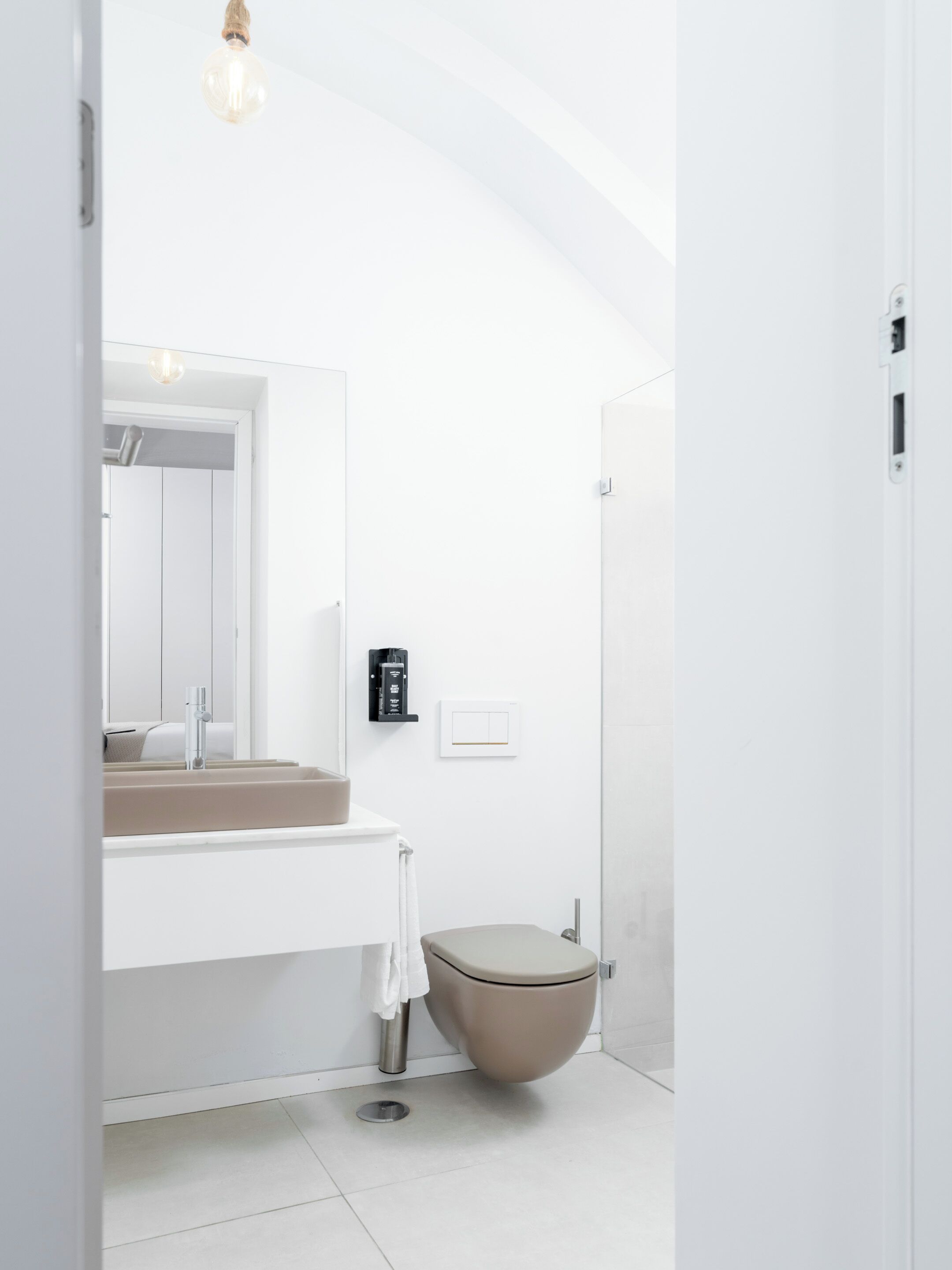 A modern bathroom with a white vanity, a toilet, and a light fixture.