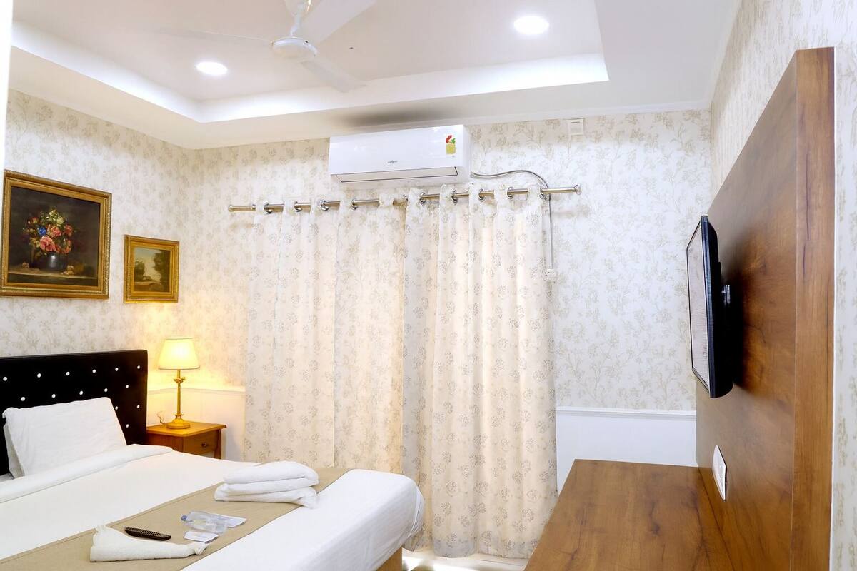 Une chambre d’hôtel équipée d’un lit, d’une table de chevet, d’une lampe, d’un climatiseur et d’un téléviseur fixé au mur.