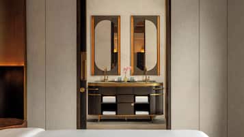 A modern bathroom with a large mirror, a vanity with a gold faucet, and a towel rack.