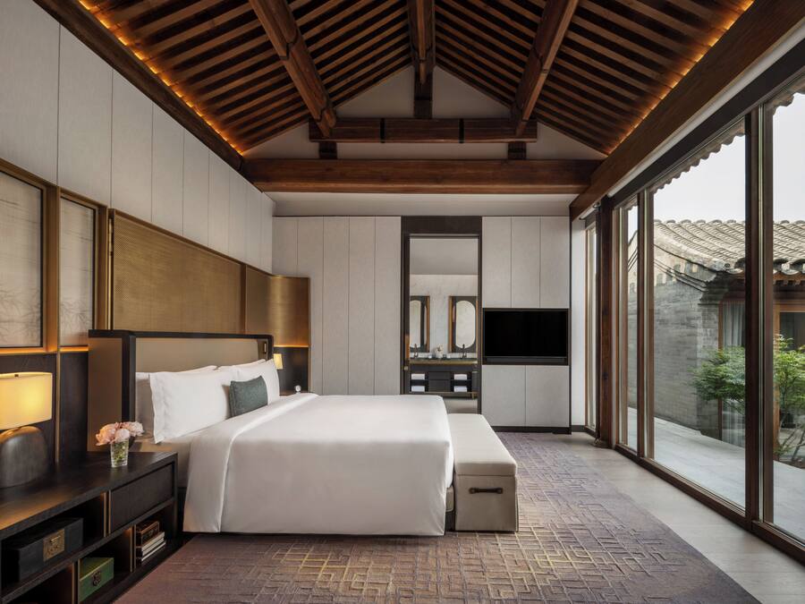 Een moderne hotelkamer met een groot bed, een televisie en uitzicht op buiten.