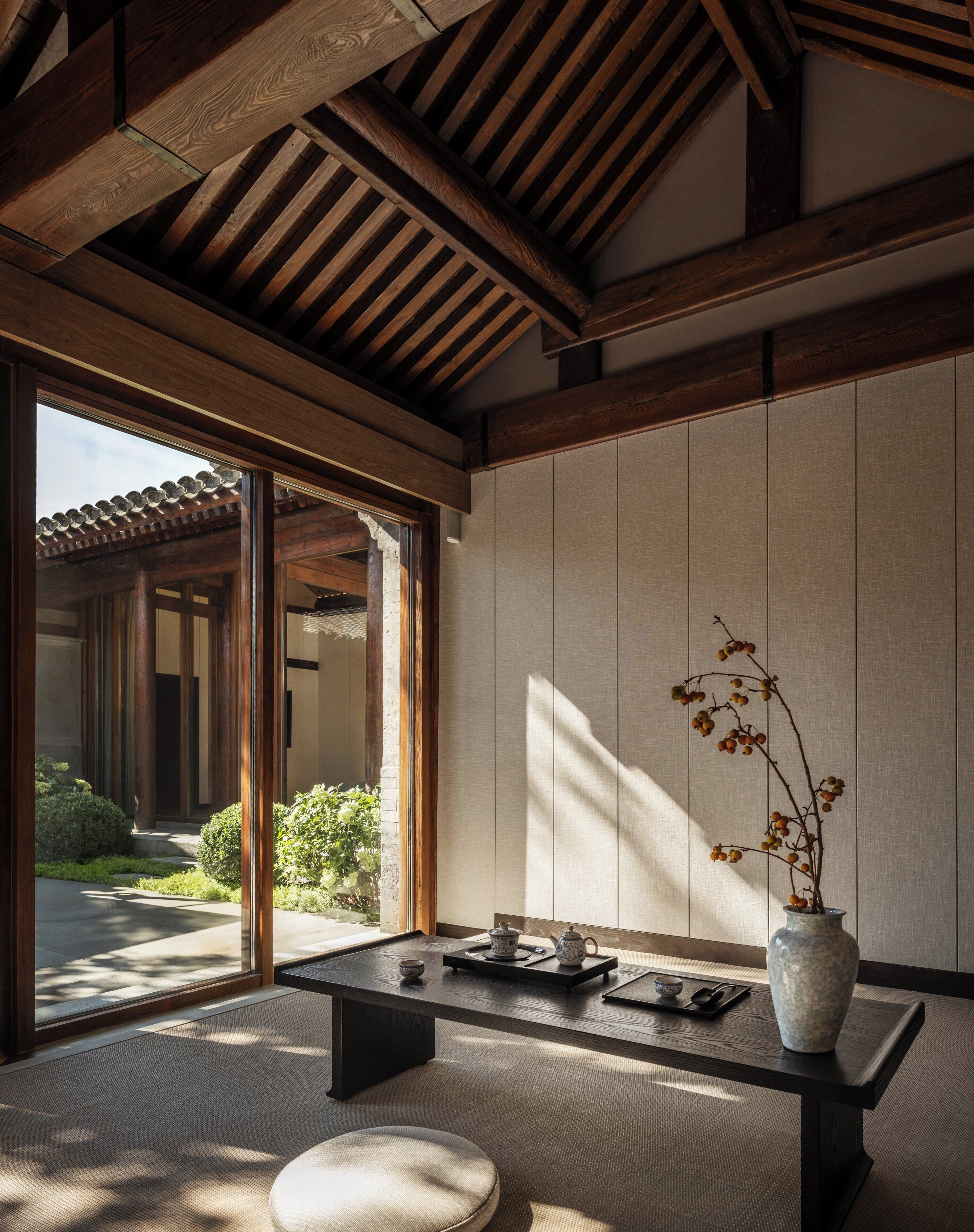 Ein traditioneller japanischer Raum mit Tatami-Boden, einem niedrigen Tisch mit Tee-Service und einer Vase mit Zweigen.