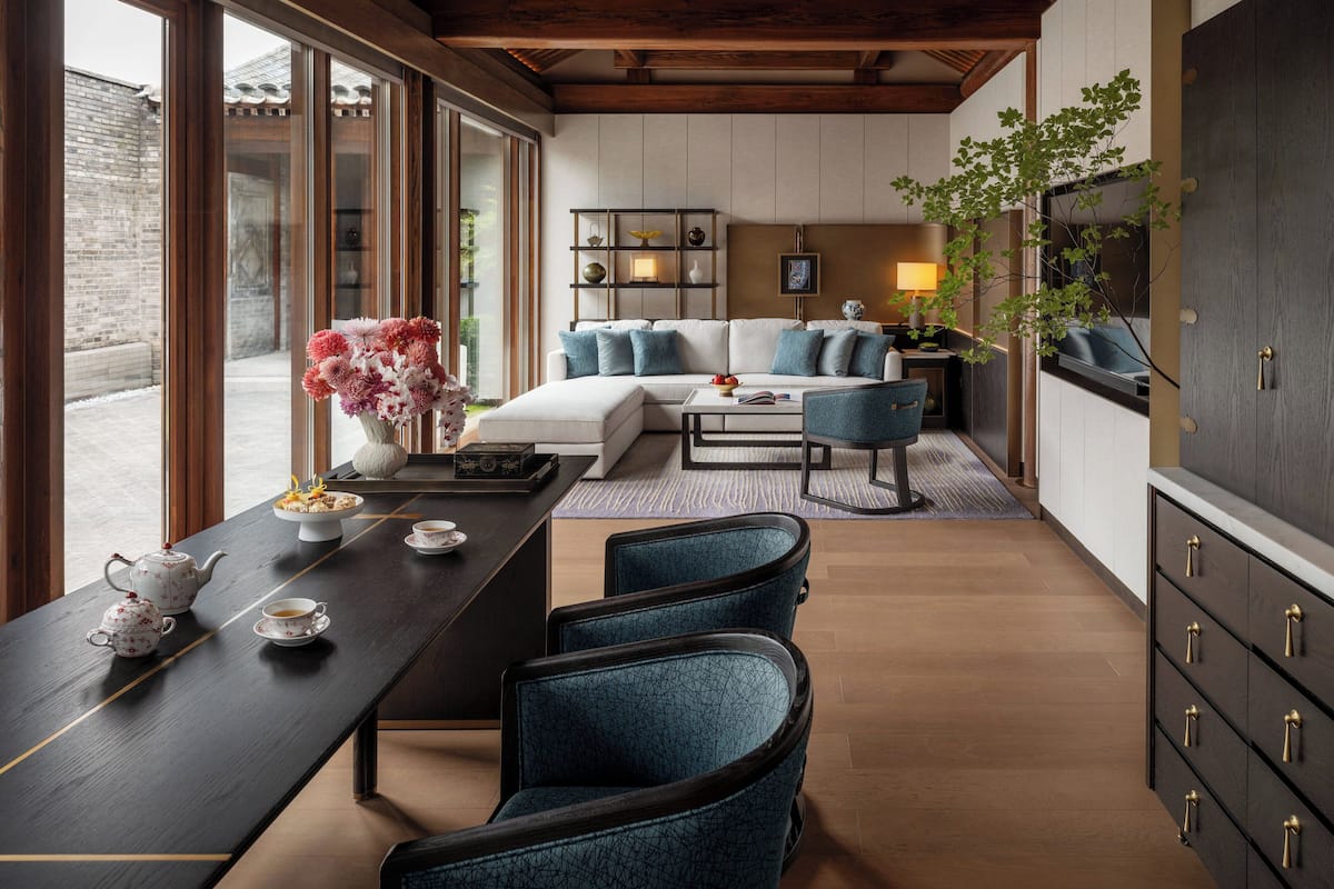 Un interior moderno con techo de madera, un conjunto de sofá, una mesa de comedor con sillas y un mueble con cajones.