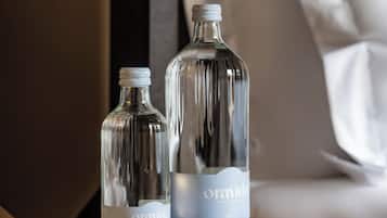 Dos botellas de vidrio con la etiqueta "Oravida" sobre una mesa de madera, junto a un bloc de notas y un bolígrafo.