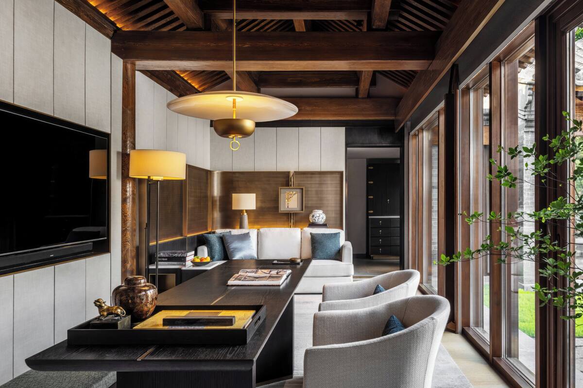 Un moderno salón con techo de madera, un televisor grande y un comedor con una mesa larga y sillas.