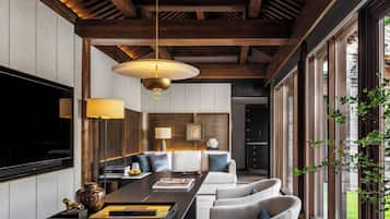 A modern living room with a wooden ceiling, a large TV, and a dining area with a long table and chairs.