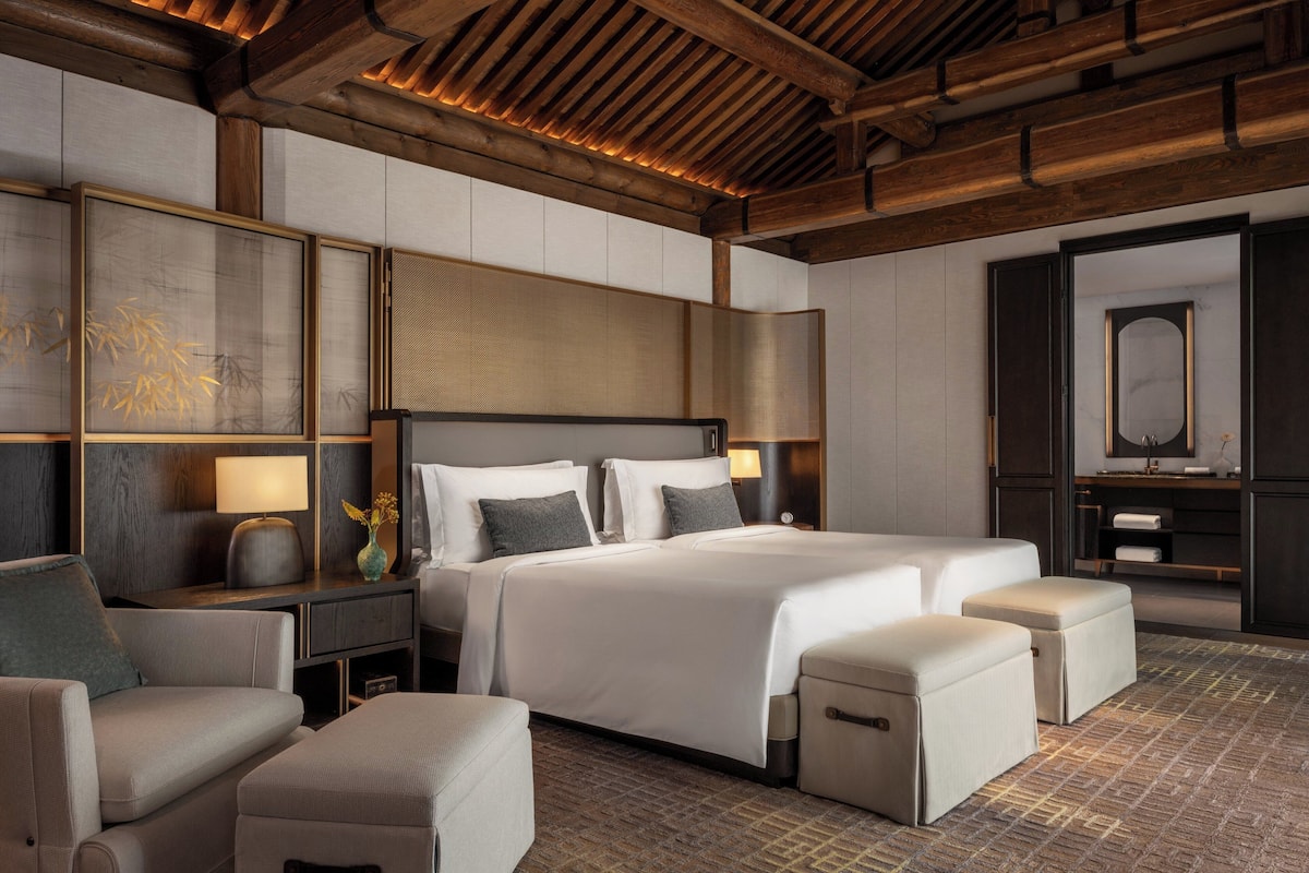 Una habitación de hotel moderna con una cama grande, un sofá, un escritorio y un espejo.