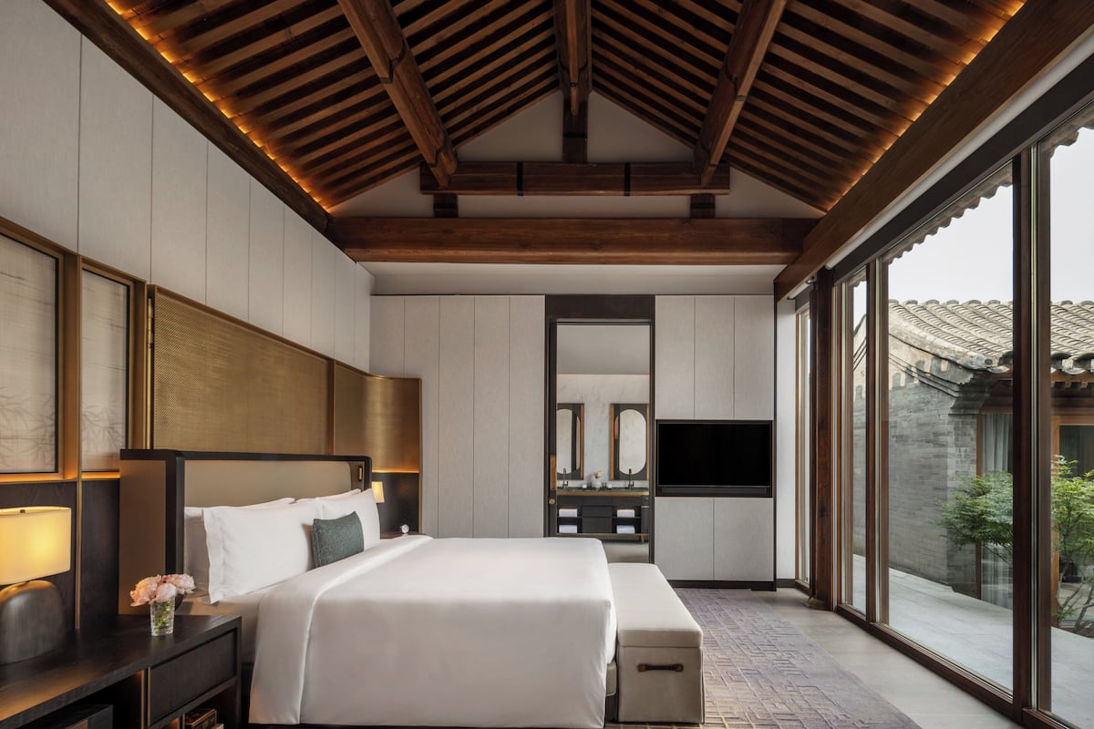 Habitación de hotel moderna con una cama grande, televisor y vista al exterior.