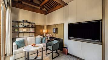 A modern living room with a sofa, a coffee table, a TV mounted on the wall, and a bookshelf.