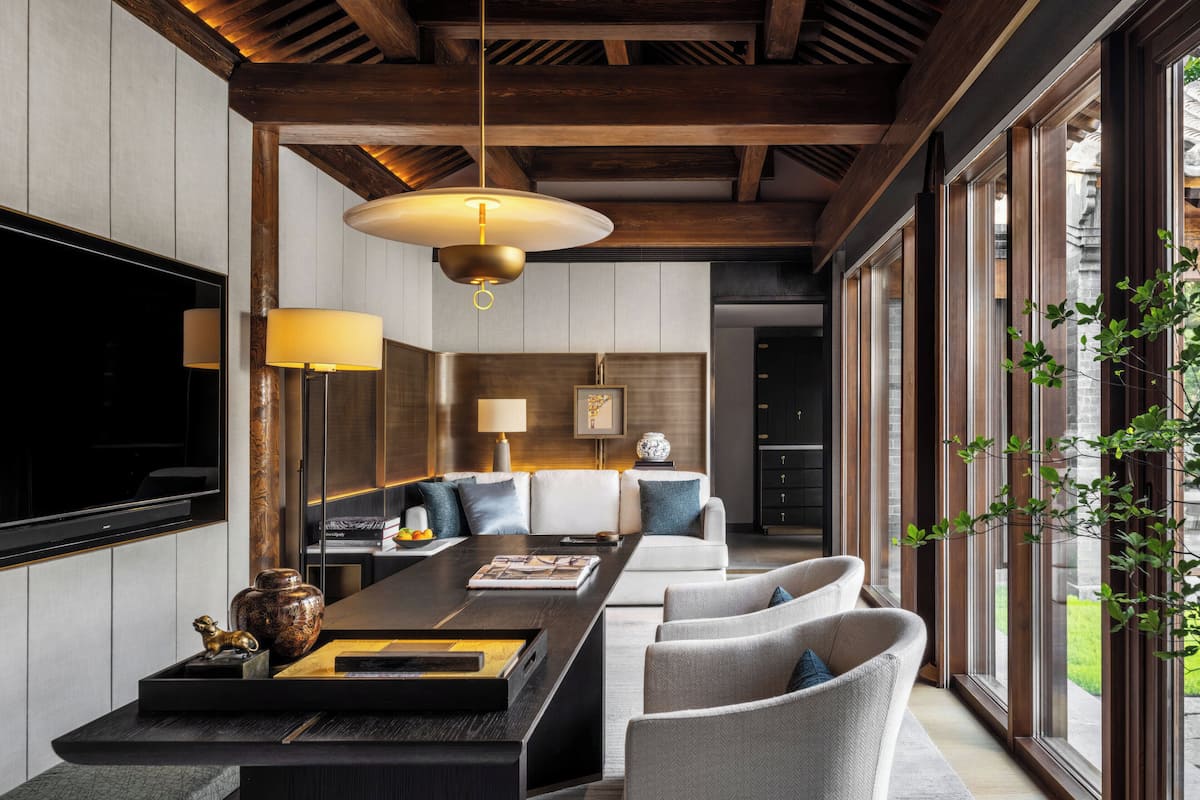 Un moderno salón con techo de madera, un televisor grande y un comedor con una mesa larga y sillas.