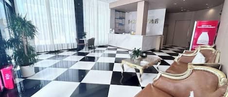A lobby with a checkered floor, seating area, and a reception desk.