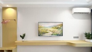 A room with a mounted painting, a built-in bench, a wall-mounted air conditioner, and a potted plant. - afuerliansuozheyujiudian (Xiushan County)