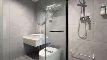 A modern bathroom with a glass-enclosed shower, a white sink, and a toilet.