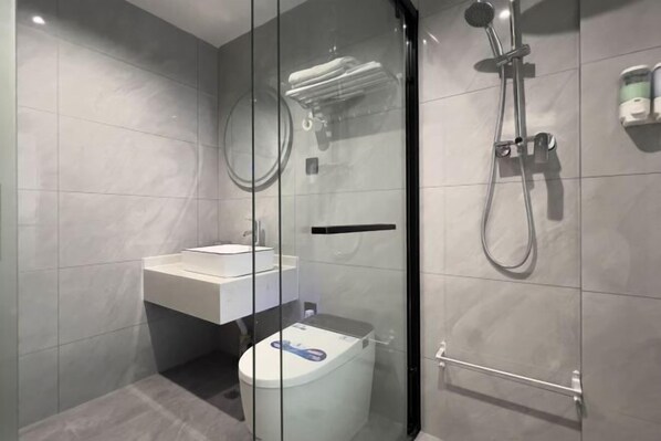 Un baño moderno con ducha de vidrio, lavamanos blanco y retrete.
