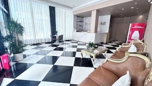 A lobby with a checkered floor, a reception desk, and a seating area with cushioned chairs. - afuerliansuozheyujiudian (Xiushan County)