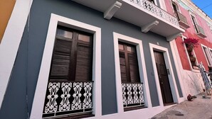 A building with a grey facade, white trim, and decorative metal railings.
