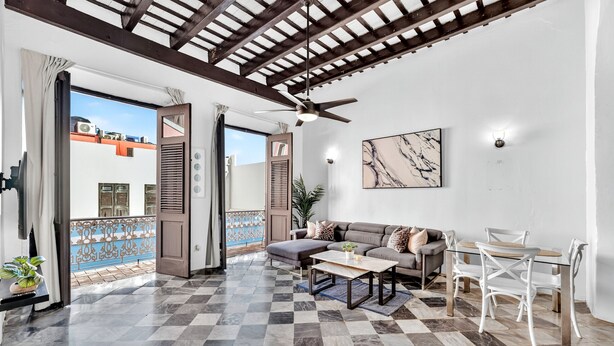 A spacious living area with a checkered floor, a sofa, a coffee table, and a dining table with chairs.