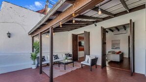 En overdækket terrasse med en sofasæt, et sofabord og en potteplante.