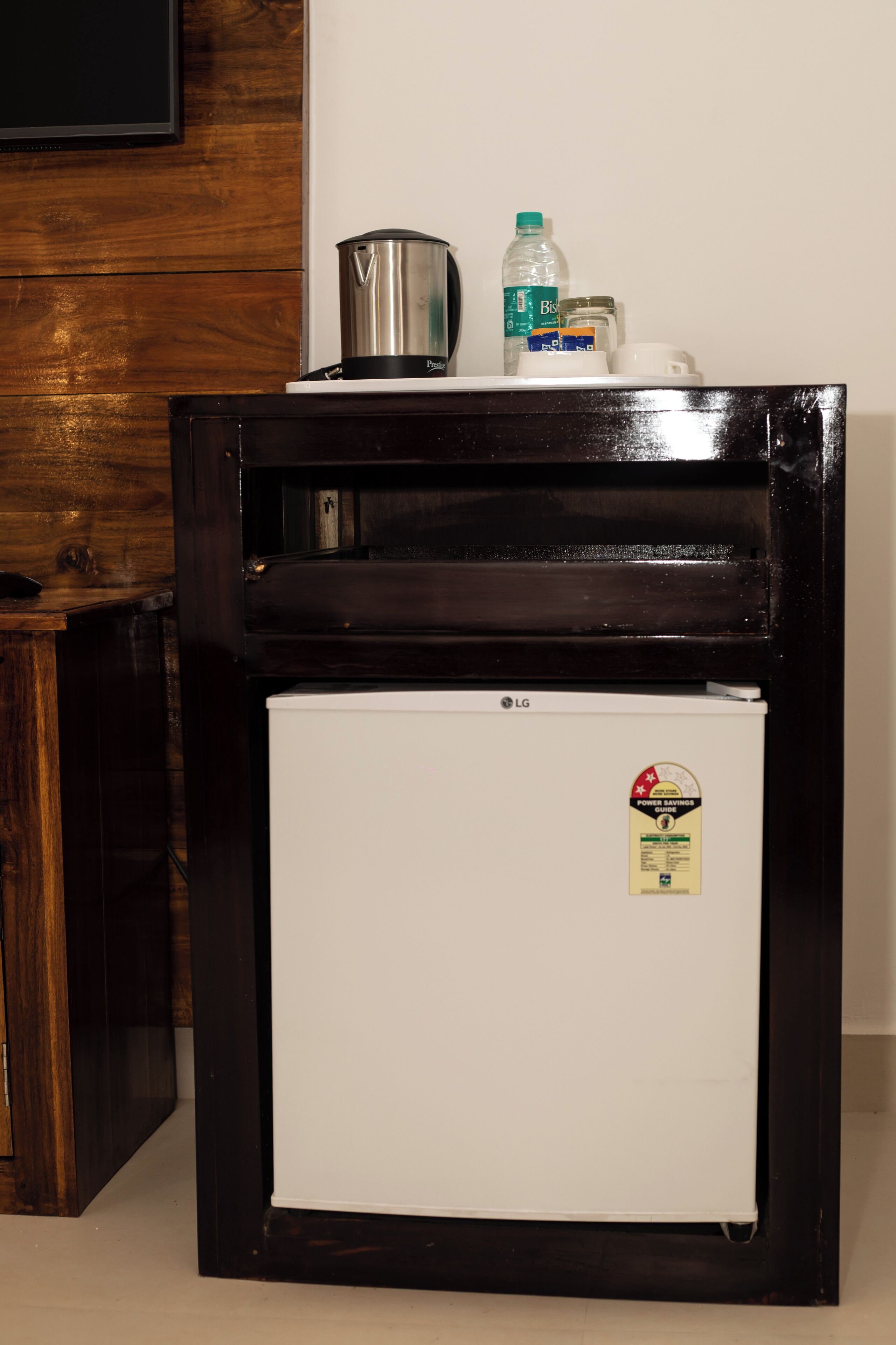 A compact refrigerator with a power savings sticker, a water bottle, and a container on top.