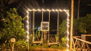 A swing set with a sign reading "The Bullion Bar & Bistro" under a canopy of lights. - The Woodside Inn Goa (Benaulim)
