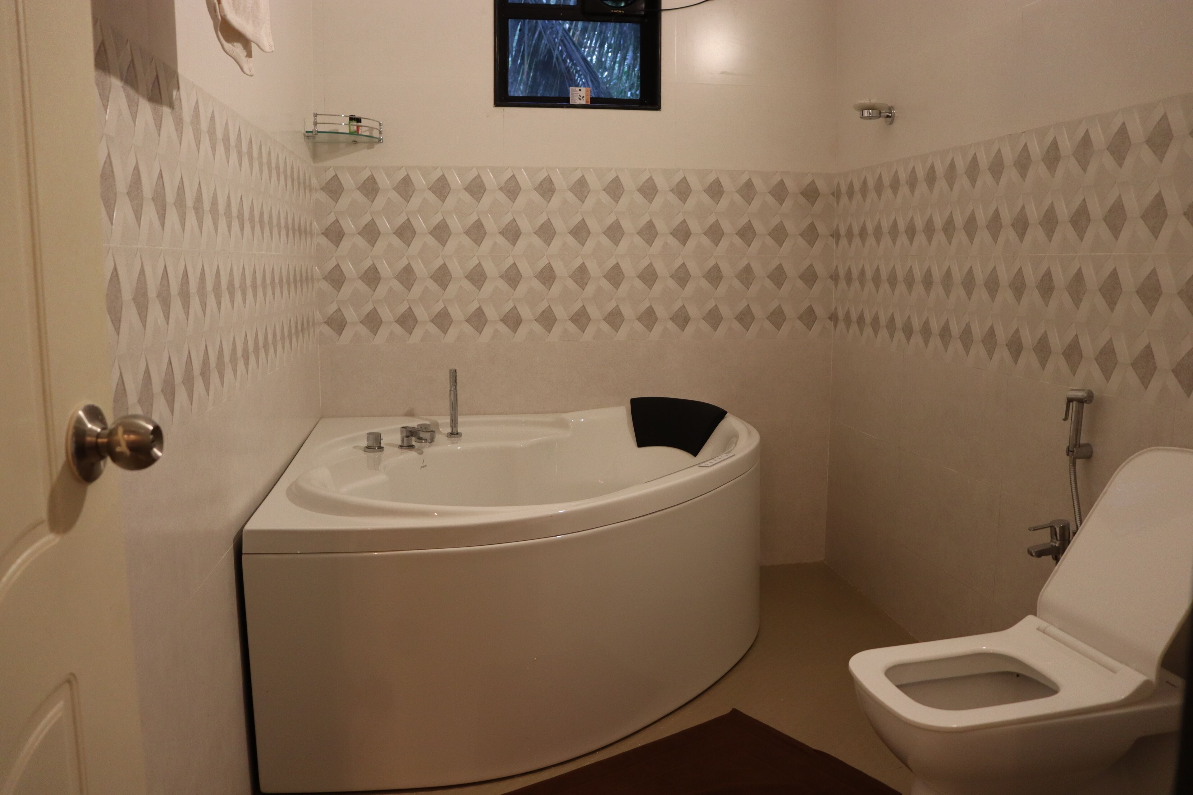 Een badkamer met een bad, toilet en een klein raam.