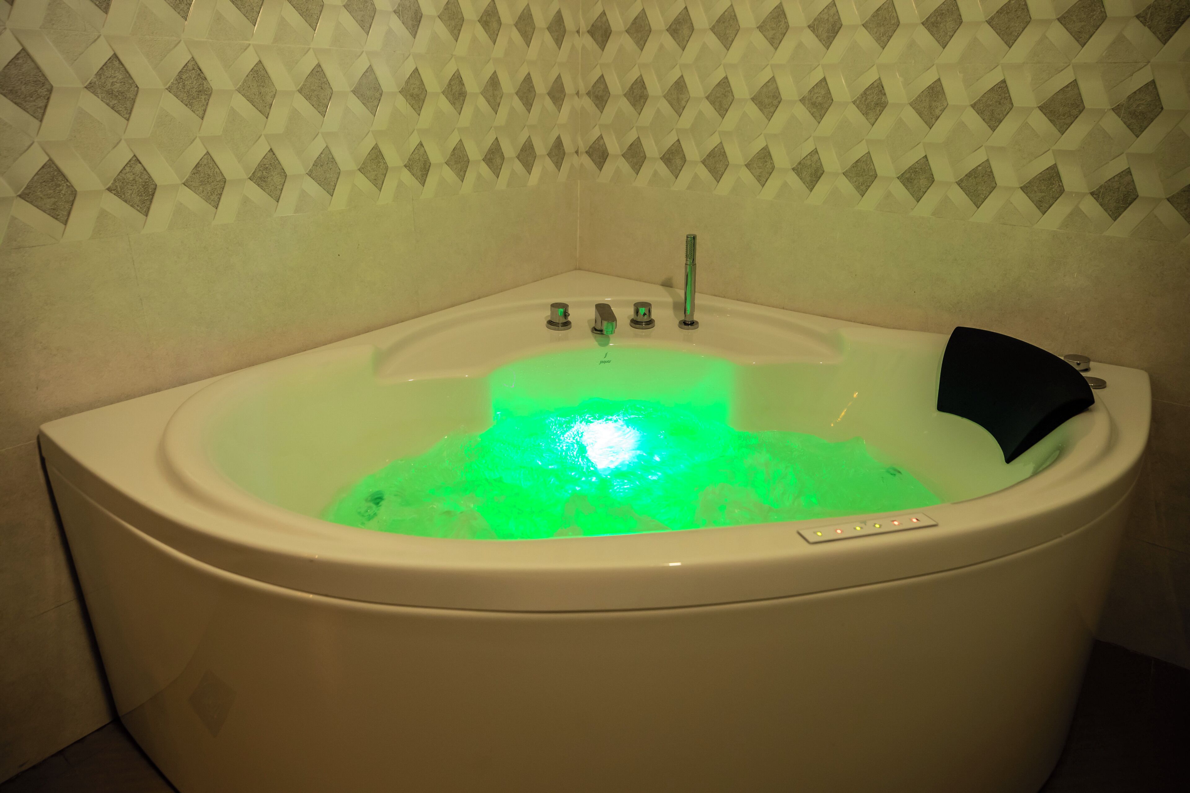 Eine Badewanne mit grüner Beleuchtung, ein schwarzes Objekt am Rand und einem Bedienfeld mit Knöpfen.