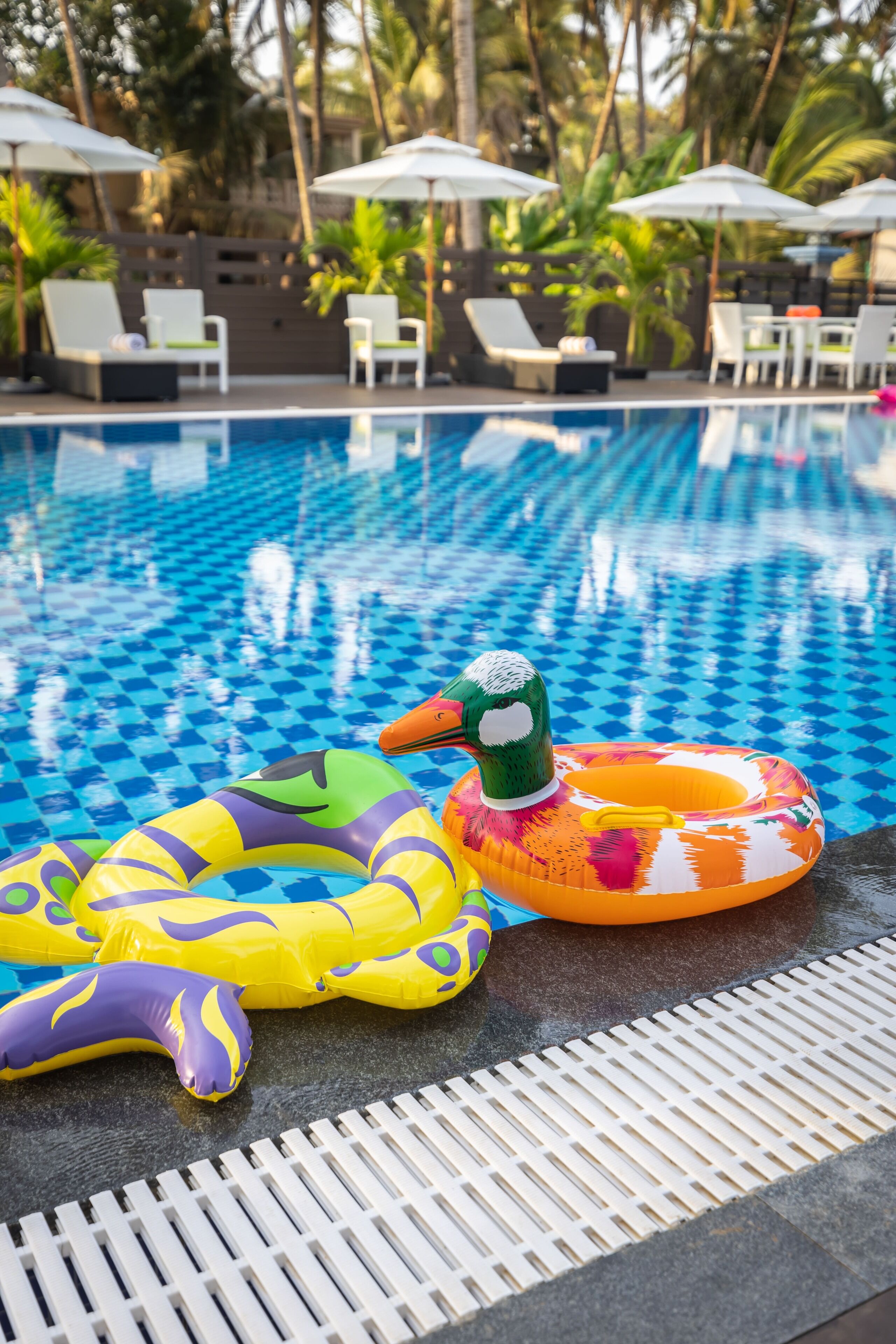 A swimming pool with inflatable rings and lounge chairs.