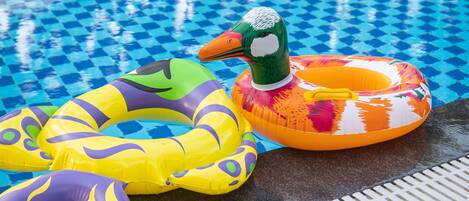 A swimming pool with inflatable rings and lounge chairs.