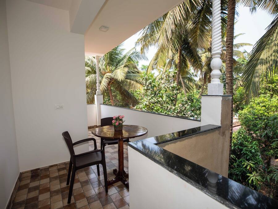 Un balcón con mesa y sillas, con vistas a un exuberante jardín de palmeras.