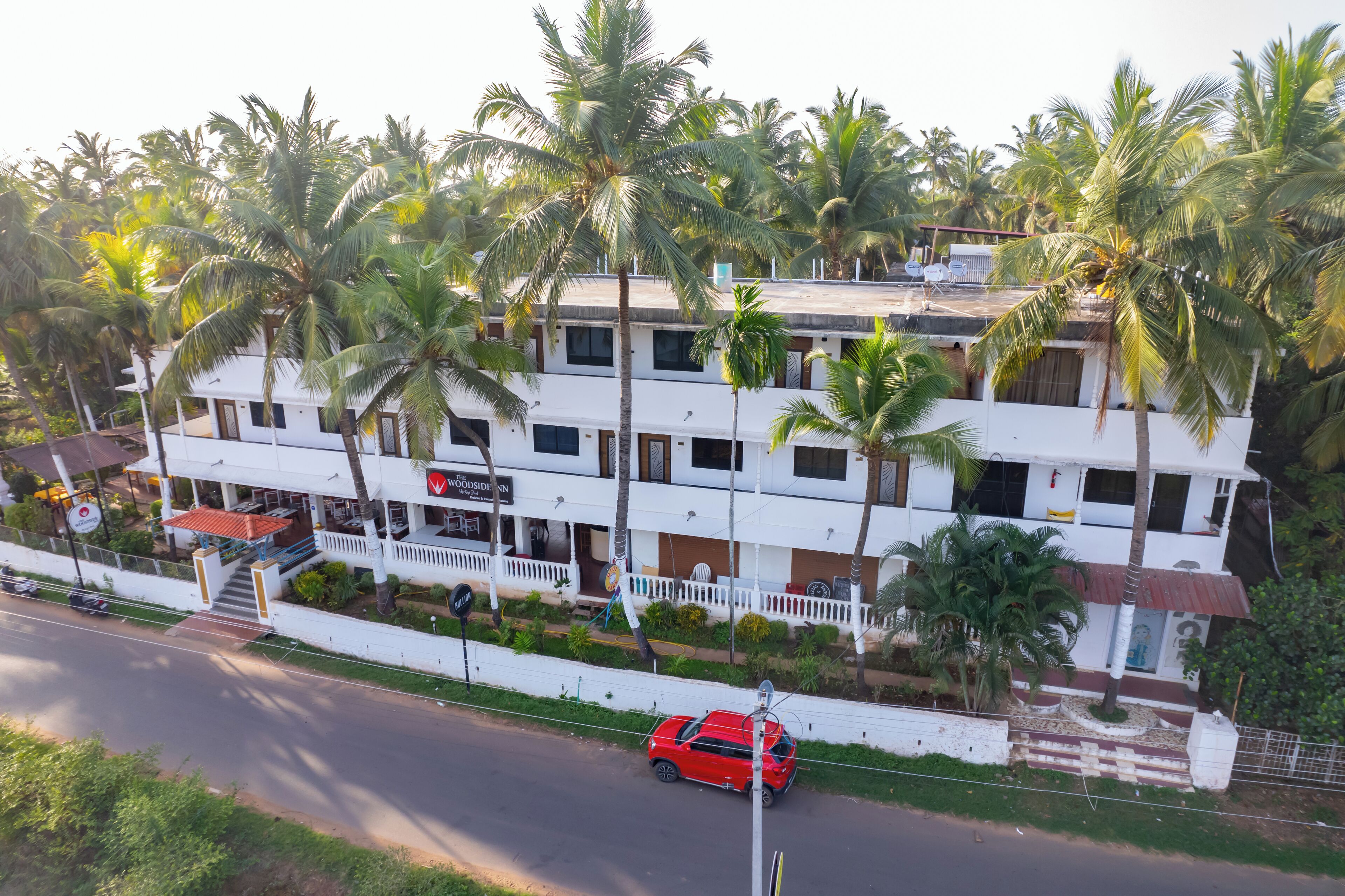 A multi-story building with a white facade, surrounded by palm trees.