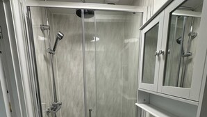A modern bathroom with a glass-enclosed shower, a white sink, and a mirror above the sink. - The Highmead (Blackwood)
