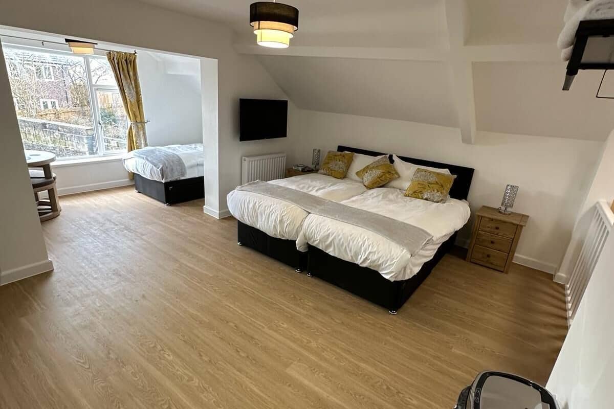 Une chambre avec un grand lit, une télévision, un radiateur et une fenêtre avec des rideaux.