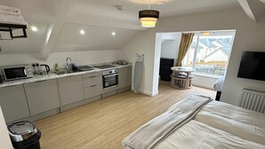 A compact, modern apartment with a kitchenette, a large bed, and a view of the outside. - The Highmead (Blackwood)