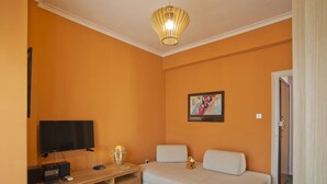 Une chambre avec un lit, une télévision, un bureau en bois et un tableau accroché au mur.