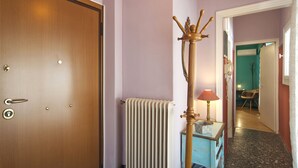 Un couloir avec une porte en bois, un radiateur, une lampe et un meuble bleu.