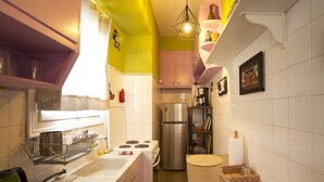 Une cuisine de taille réduite, équipée d’un réfrigérateur en acier inoxydable, d’une cuisinière à gaz et d’un évier.