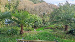 A bench in a garden with various plants and trees. - Le Jardin Saint Germain Lodges & Events (Plogastel-Saint-Germain)