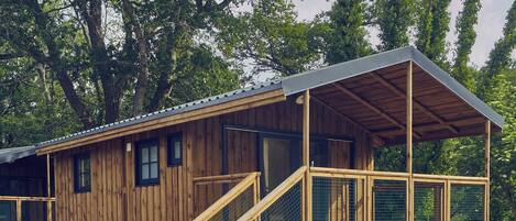 A wooden cabin with a covered porch and a staircase leading to the entrance.