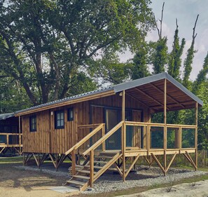 A wooden cabin with a covered porch and a staircase leading to the entrance. - Le Jardin Saint Germain Lodges & Events (Plogastel-Saint-Germain)
