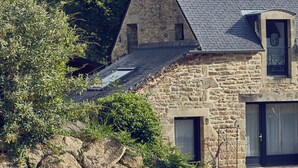 A stone house with a sloped roof, a chimney, and a small window. - Le Jardin Saint Germain Lodges & Events (Plogastel-Saint-Germain)