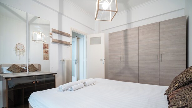 Ein Schlafzimmer mit einem großen Bett, einem Schminktisch, einem Spiegel und einem Kleiderschrank.
