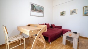 Ein Zimmer mit einem Holztisch, einem roten Sofa und einem kleinen Tisch mit Tasse und Untertasse.