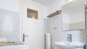 Ein kleines, sauberes Badezimmer mit Toilette, Waschbecken und Spiegel.