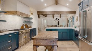 A spacious kitchen with a central island, wooden beams, and modern appliances. - Luxury cabin w/ chef kitchen & two living rooms (Highlands)