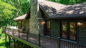 A cabin with a stone exterior, a deck, and large windows. - Luxury cabin w/ chef kitchen & two living rooms (Highlands)