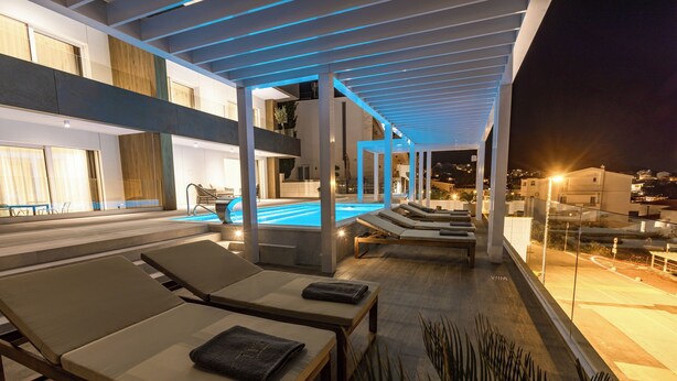 Un área de piscina en la azotea con sillones de descanso y una piscina.